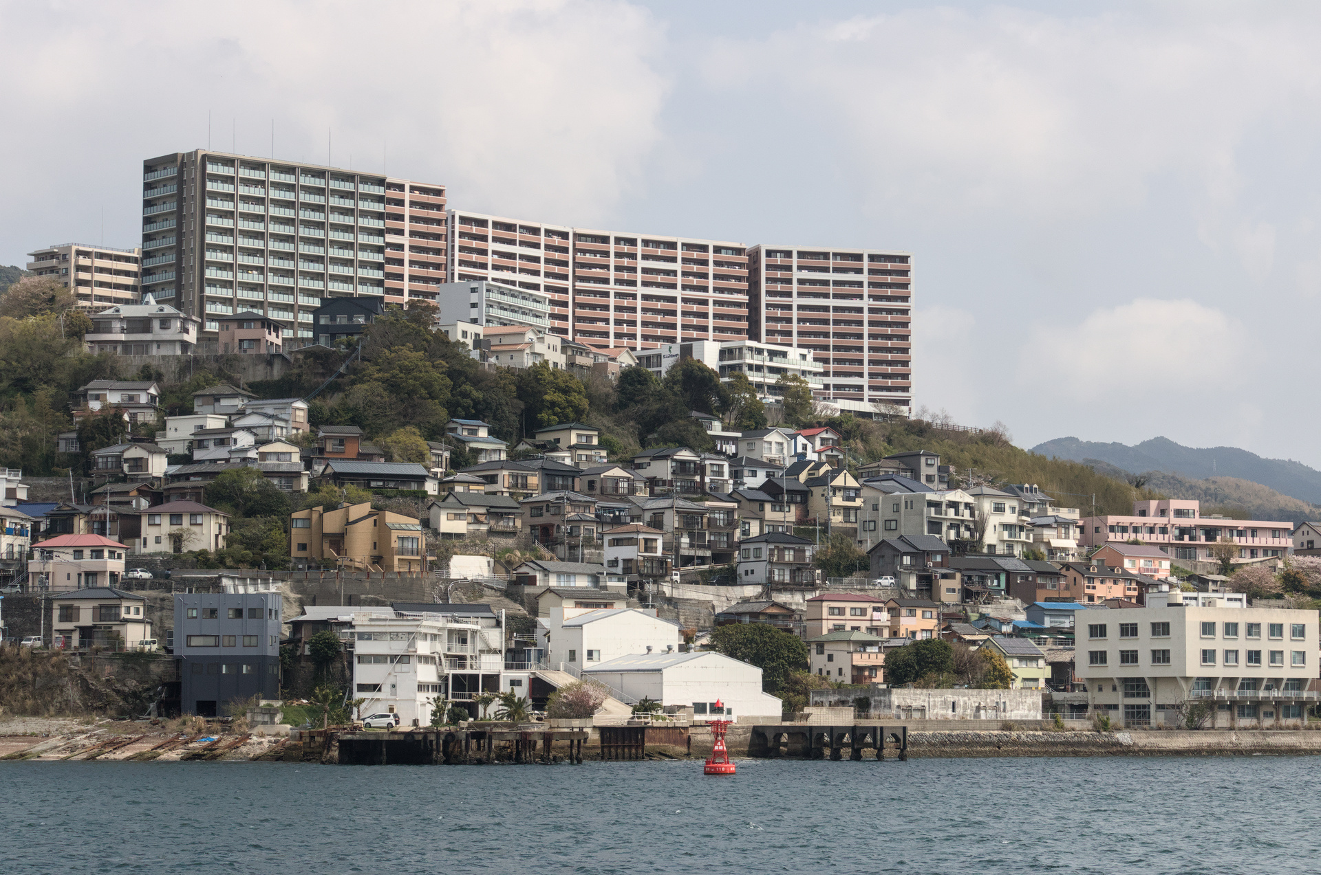 Packed small buildings on the water's shore with larger apartment buildings standing right behind them.